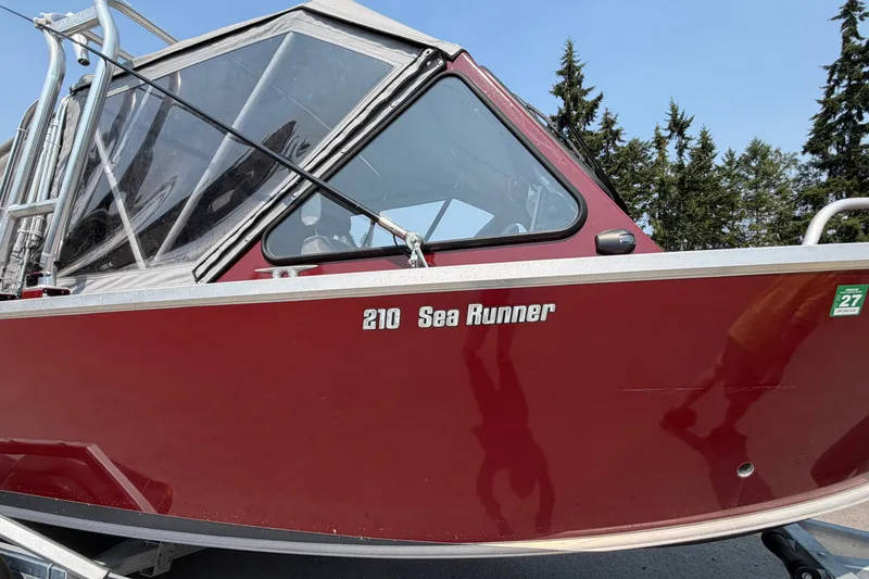 Slide: The Image of 2024 Hewescraft 210 Sea Runner ET boat with red exterior and sleek design. - 17