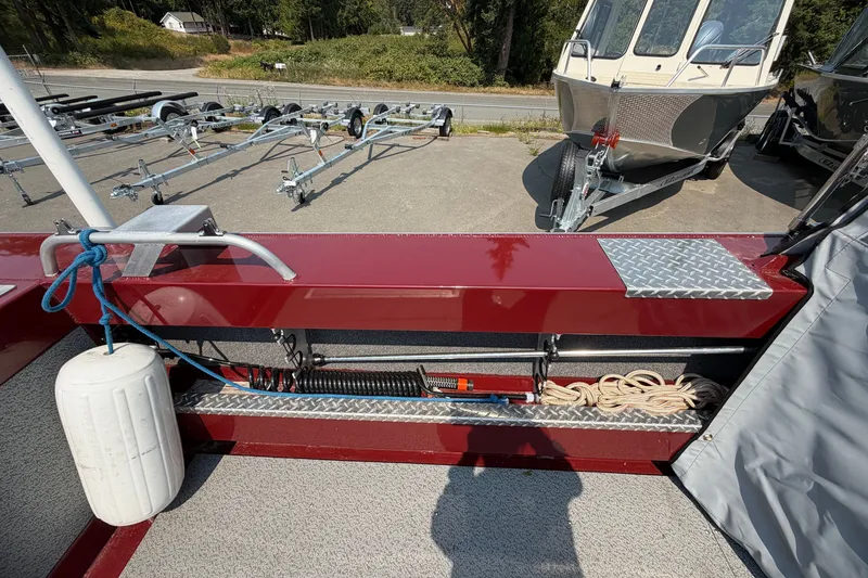Slide: The Image of 2024 Hewescraft 210 Sea Runner ET boat interior with storage, ropes, and trailer view. - 13