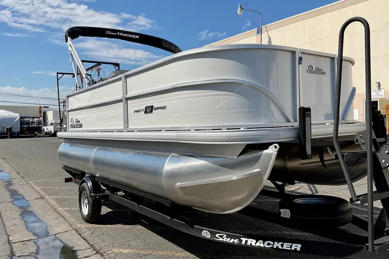 The Image of 2026 Sun Tracker Party Barge 18 DLX pontoon boat on trailer, parked outdoors. - 0