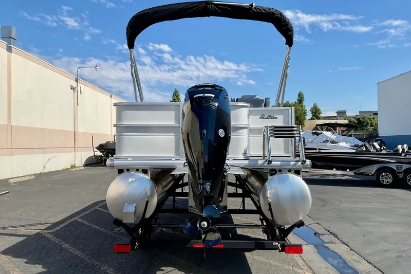 Slide: The Image of 2026 Sun Tracker Party Barge 18 DLX pontoon boat with outboard motor in a parking lot. - 18