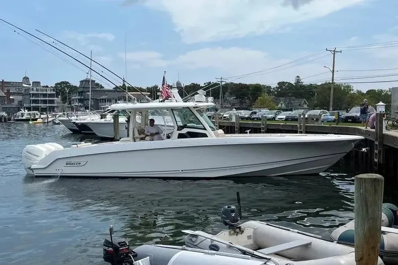 The Image of 2021 Boston Whaler 380 Outrage docked at a marina, showcasing sleek design and fishing rods. - 1