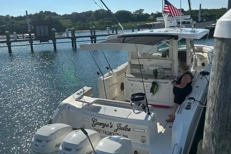 Slide: The Image of 2021 Boston Whaler 380 Outrage docked, featuring a person onboard, with scenic waterfront view. - 8