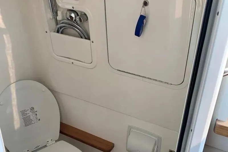 Slide: The Image of 2019 Boston Whaler 380 Outrage boat bathroom interior with toilet and storage compartment. - 25