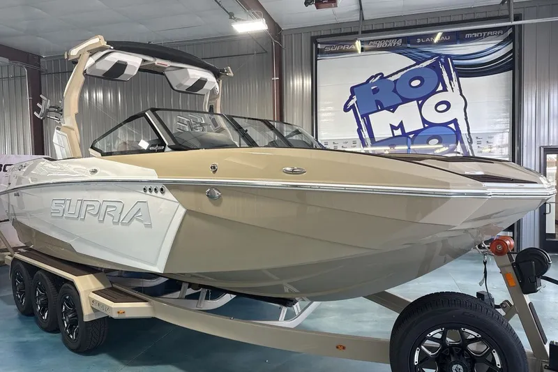 Slide: The Image of 2027 Supra SL 550 boat in showroom, beige and white design, on a trailer. - 43