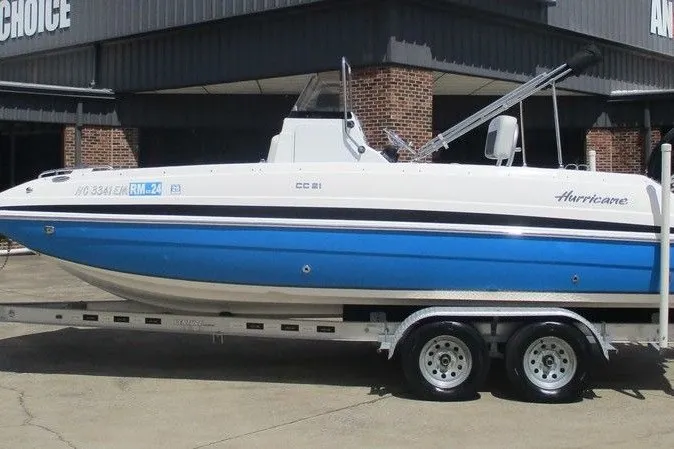 The Image of 2019 Hurricane SunDeck Sport CC 231 OB boat on trailer, blue and white design. - 1