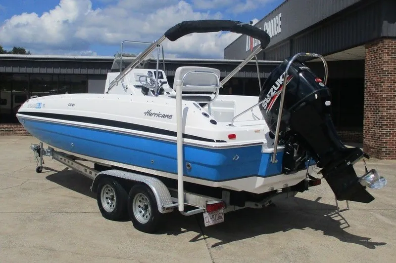 Slide: The Image of 2019 Hurricane SunDeck Sport CC 231 OB boat on trailer, blue and white design. - 2