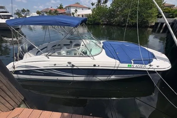 The Image of 2013 Hurricane SunDeck 2400 OB boat docked, featuring blue canopy and cover. - 1