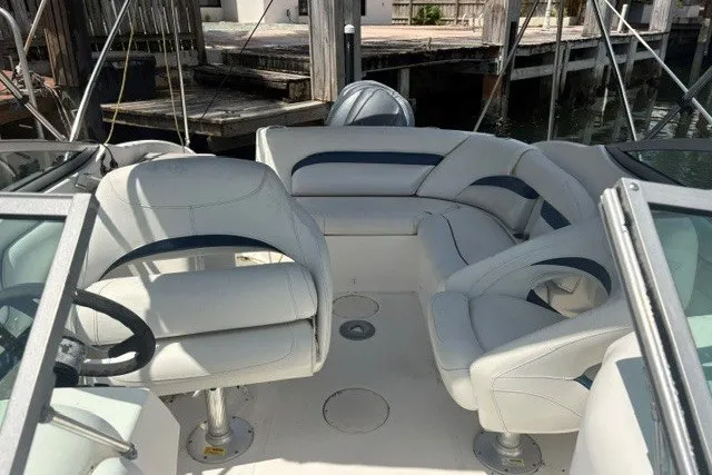 Slide: The Image of 2013 Hurricane SunDeck 2400 OB boat interior with white seating and steering wheel. - 7
