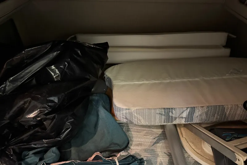 Slide: The Image of Interior storage area of a 1994 Sea Ray 300 Sundancer boat with cushions and bags. - 16