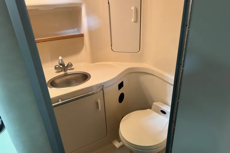 Slide: The Image of Compact bathroom in 1994 Sea Ray 300 Sundancer boat, featuring sink and toilet. - 15