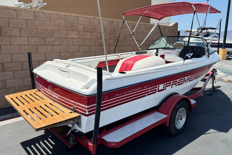 Slide: The Image of 1991 Ski Supreme MS Tournament Series boat with red accents and trailer, parked outdoors. - 5