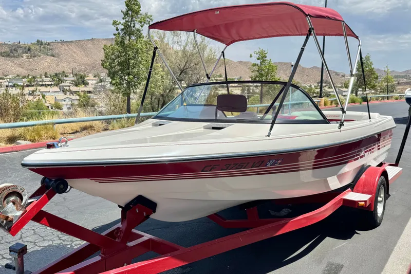 Slide: The Image of 1991 Ski Supreme MS Tournament Series boat with red canopy on trailer, parked outdoors. - 3