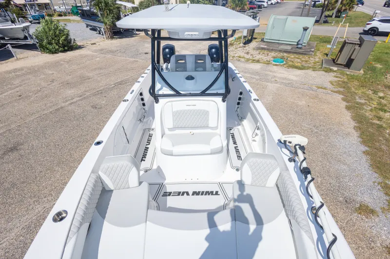 Slide: The Image of 2022 Twin Vee 240 GFX CC boat interior with seating and console, parked outdoors. - 42