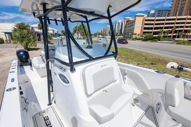 Slide: The Image of 2022 Twin Vee 240 GFX CC boat with sleek design, parked near a coastal road. - 49