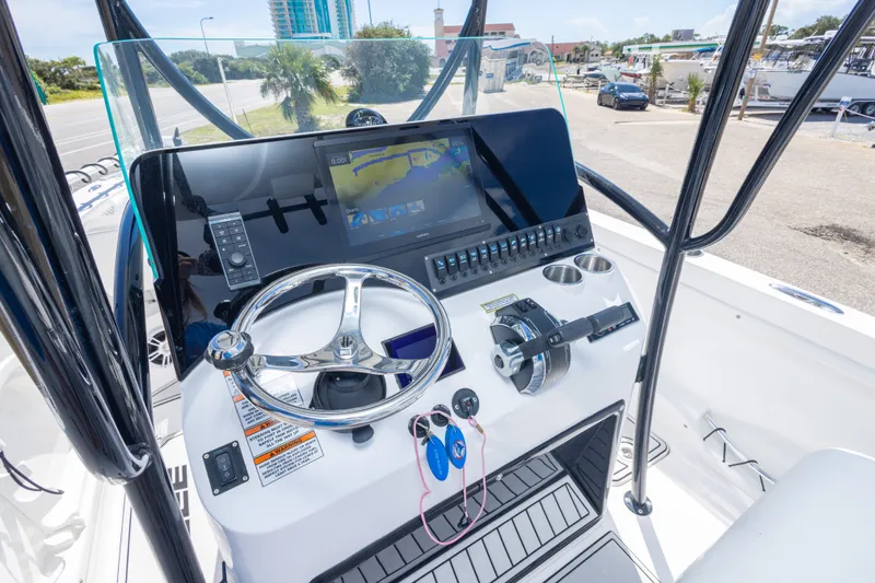Slide: The Image of 2022 Twin Vee 240 GFX CC boat dashboard with steering wheel and navigation display. - 32