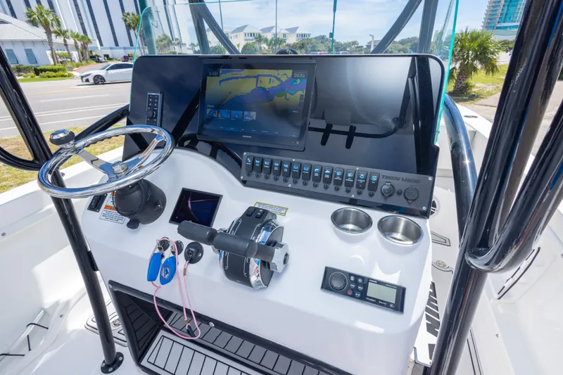 Slide: The Image of 2022 Twin Vee 240 GFX CC boat dashboard with steering wheel and navigation display. - 33
