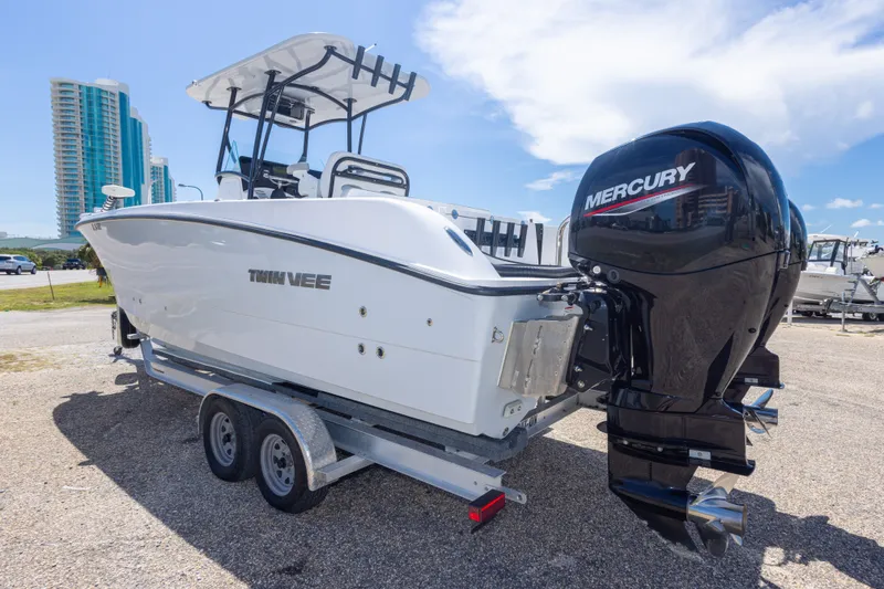 Slide: The Image of 2022 Twin Vee 240 GFX CC boat with Mercury engines on a trailer, cityscape background. - 20