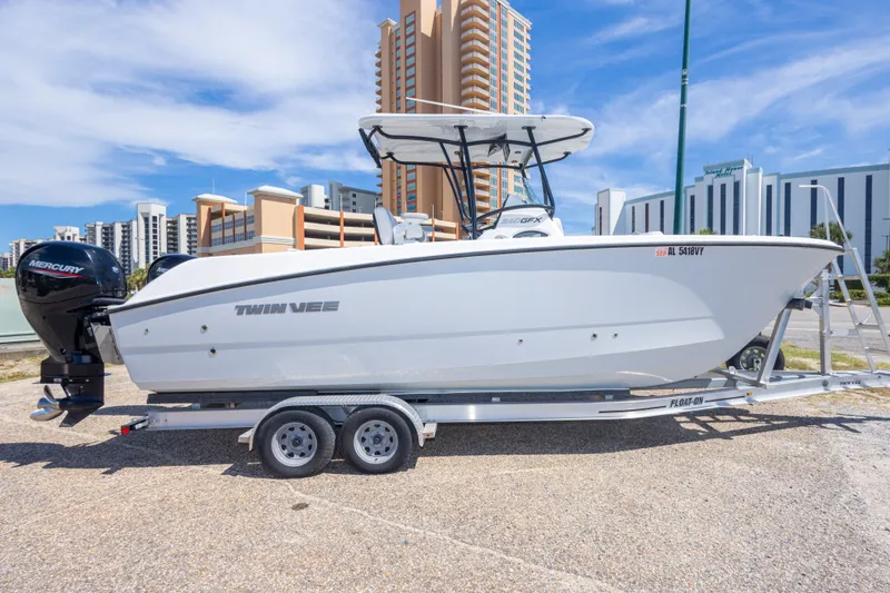 Slide: The Image of 2022 Twin Vee 240 GFX CC boat on trailer, urban background, clear sky. - 17