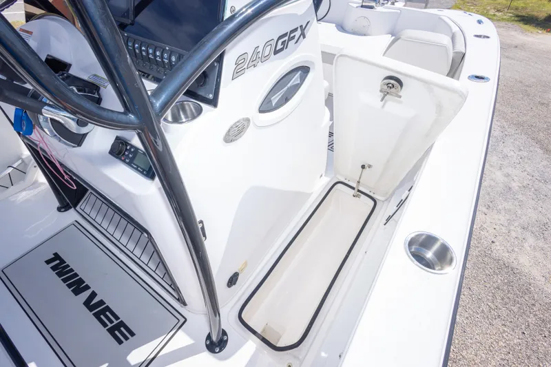 Slide: The Image of 2022 Twin Vee 240 GFX CC boat interior with open storage compartment and control panel. - 60