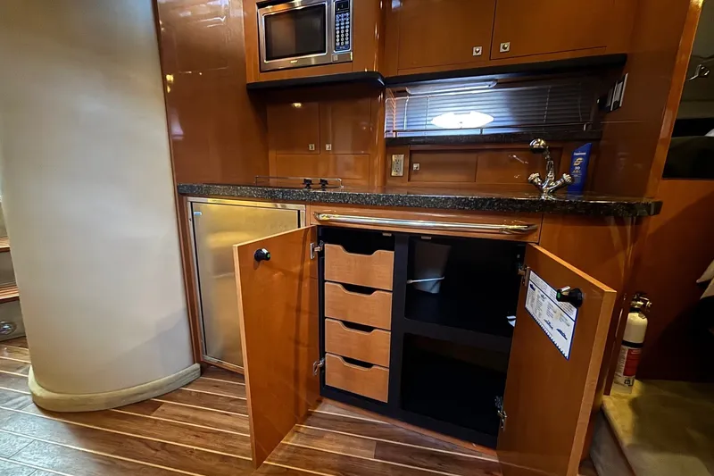 Slide: The Image of Chaparral Signature 370 2010 yacht kitchen with open cabinets, microwave, and sleek wood finish. - 28