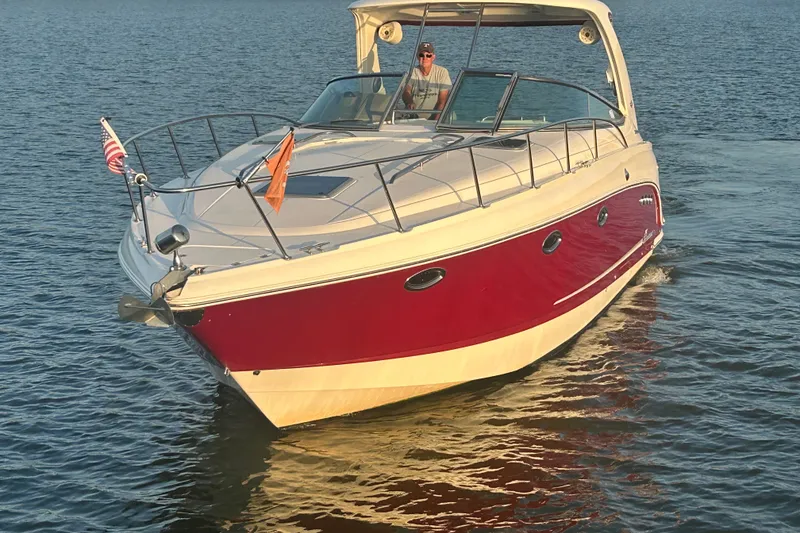 The Image of 2010 Chaparral Signature 370 boat cruising on calm water, featuring a sleek red and white design. - 7