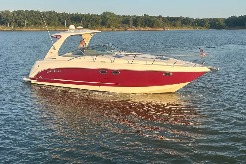 Slide: The Image of 2010 Chaparral Signature 370 boat cruising on a serene lake with lush green shoreline. - 10