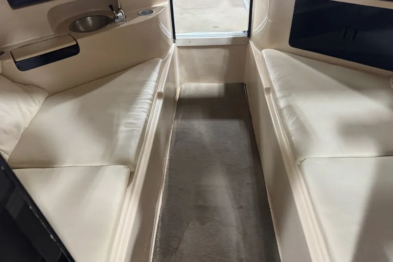 Slide: The Image of Interior of a 2000 Mariah 302 Shabah boat, featuring beige seating and a compact sink. - 11