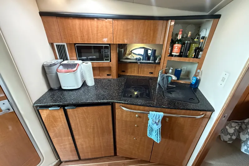 Slide: The Image of Compact kitchen in a 2003 Maxum 3700 SCR yacht with appliances and wooden cabinetry. - 36