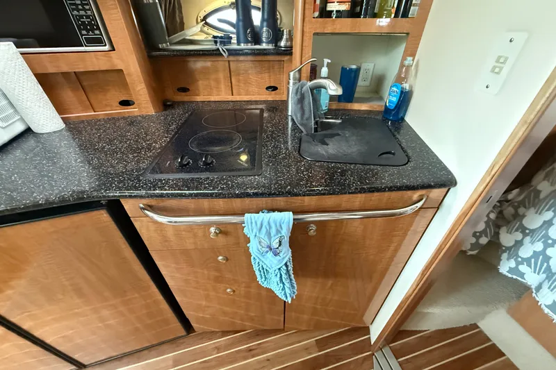Slide: The Image of 2003 Maxum 3700 SCR yacht kitchen with stove, sink, and wooden cabinetry. - 38