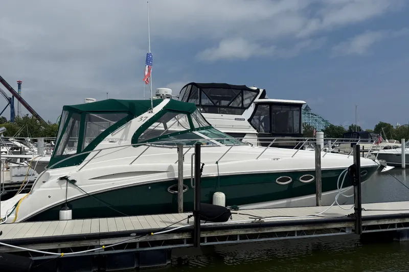 The Image of 2003 Maxum 3700 SCR yacht docked at marina with green canopy and American flag. - 3