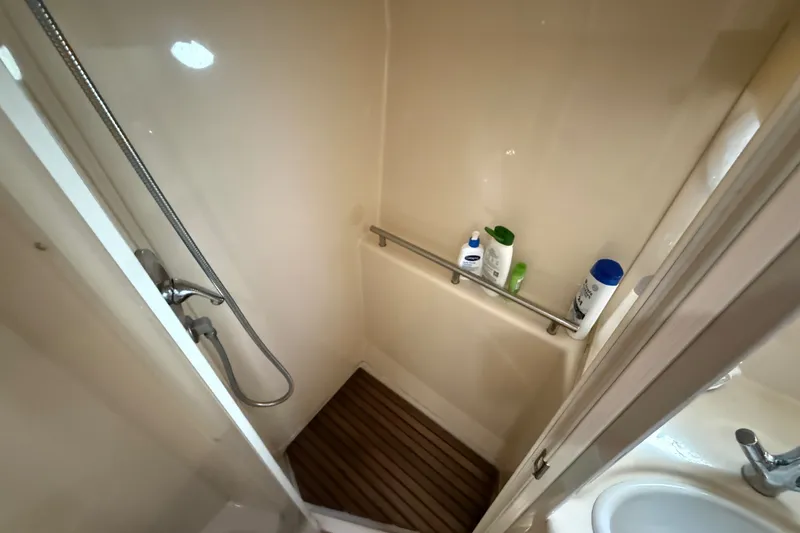 Slide: The Image of Compact shower area in a 2003 Maxum 3700 SCR boat, featuring toiletries and a handheld showerhead. - 52
