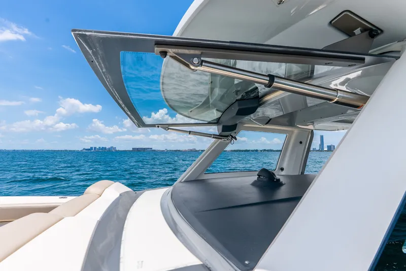 Slide: The Image of 2024 Solace 41CS boat with open windshield, ocean view, and city skyline in the background. - 23