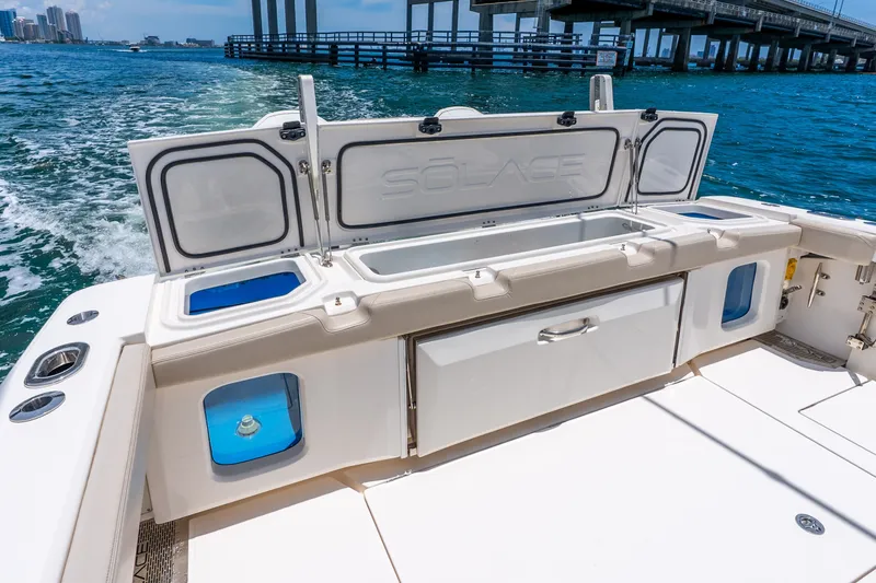 Slide: The Image of 2024 Solace 41CS boat deck with open storage compartments, cruising on blue water near a bridge. - 28
