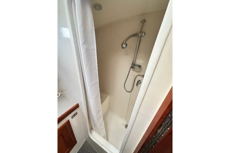 Slide: The Image of Shower area in 2001 Northern Bay 36 boat, featuring a curtain and handheld showerhead. - 24