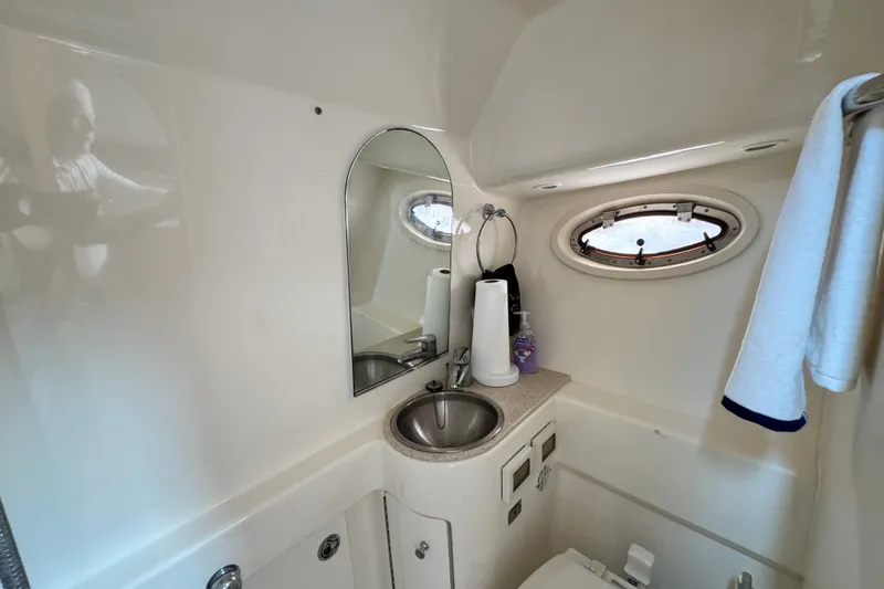 Slide: The Image of Compact bathroom in a 2008 Tiara 3000 Open yacht, featuring a sink, mirror, and porthole. - 25