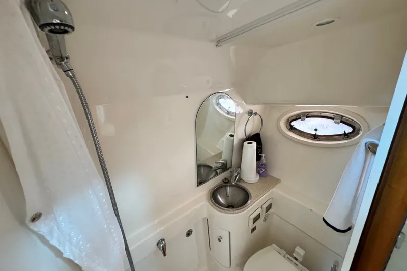 Slide: The Image of Compact bathroom in a 2008 Tiara 3000 Open yacht, featuring sink, shower, and porthole window. - 26