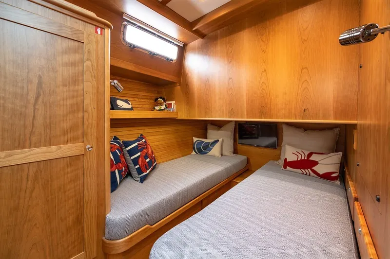 Slide: The Image of Cozy cabin interior of 2027 Sabre 45 Salon Express with wooden finish and nautical-themed pillows. - 12