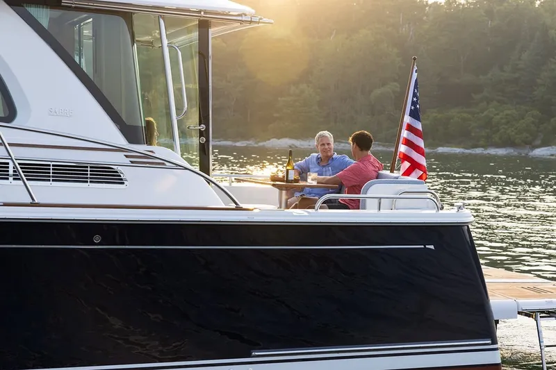Slide: The Image of Two people enjoying drinks on a 2027 Sabre 45 Salon Express yacht. - 18