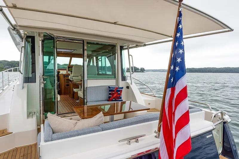Slide: The Image of 2027 Sabre 45 Salon Express yacht with American flag, elegant interior, and scenic water view. - 2