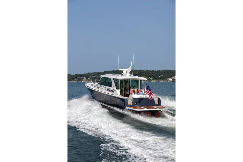 Slide: The Image of 2027 Sabre 45 Salon Express yacht cruising on open water with American flag. - 17