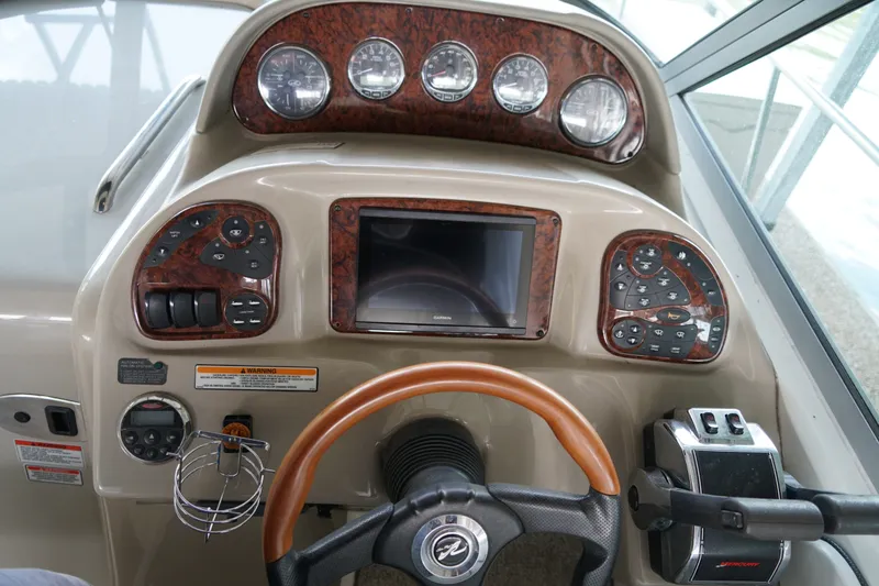 Slide: The Image of 2006 Sea Ray 300 Sundancer helm with wood accents and modern controls. - 19
