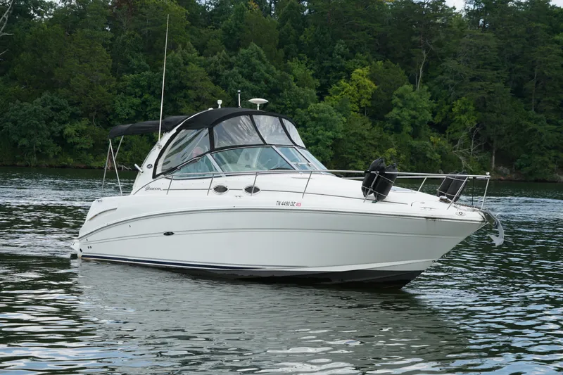 The Image of 2006 Sea Ray 300 Sundancer boat on a serene lake with lush green trees. - 0