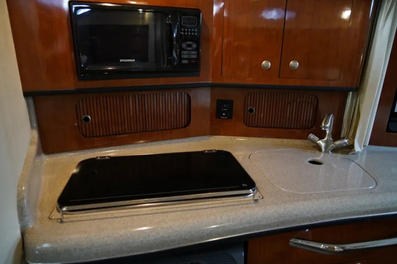 Slide: The Image of 2006 Sea Ray 300 Sundancer galley with microwave, stove, and sink. - 27