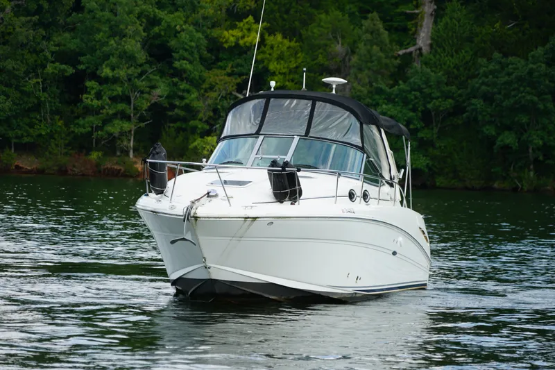 Slide: The Image of 2006 Sea Ray 300 Sundancer boat cruising on a serene lake with lush green trees. - 13