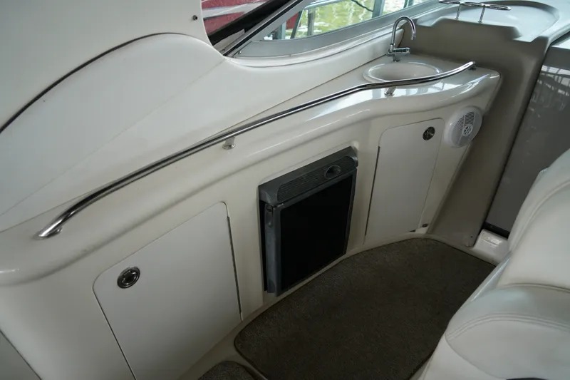 Slide: The Image of 2006 Sea Ray 300 Sundancer interior with sink, storage cabinets, and carpeted flooring. - 16