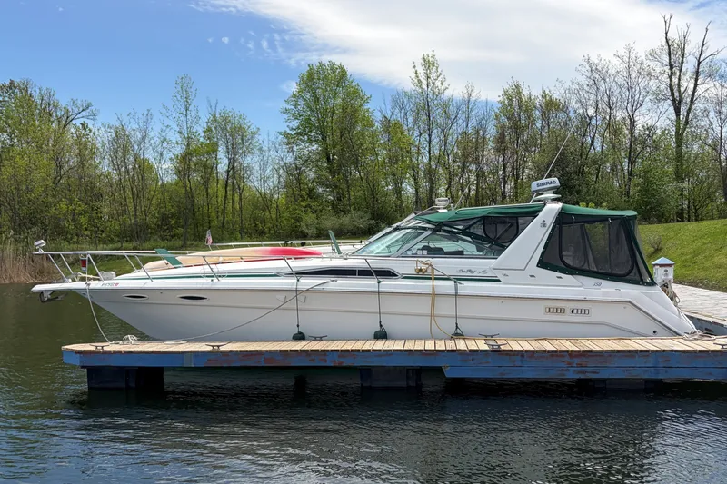 The Image of 1991 Sea Ray 350 Express Cruiser docked on a serene lake with lush greenery. - 1
