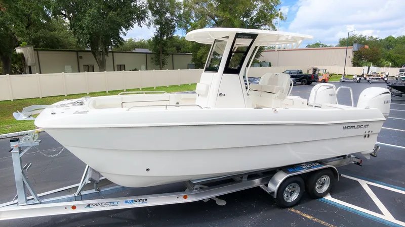 The Image of A white World Cat 235 TE boat on a trailer in a parking lot. - 1
