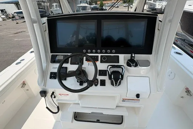 Slide: The Image of 2027 Regulator 30XO boat dashboard with dual screens and steering wheel in a marina setting. - 14