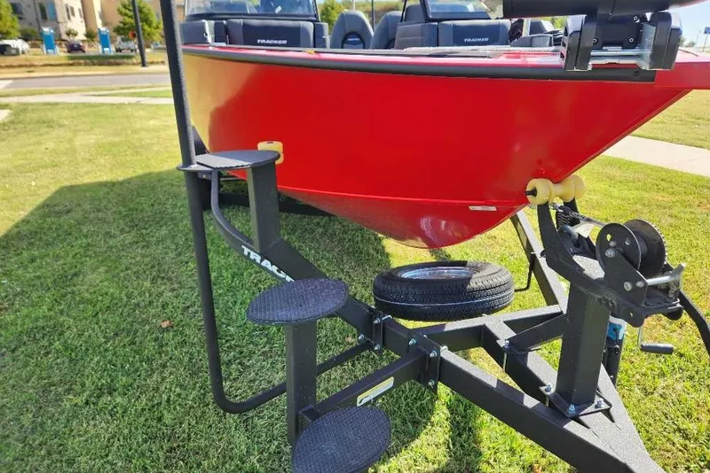 Slide: The Image of 2026 Tracker Targa V-19 WT boat on trailer, vibrant red hull, parked on grass. - 13