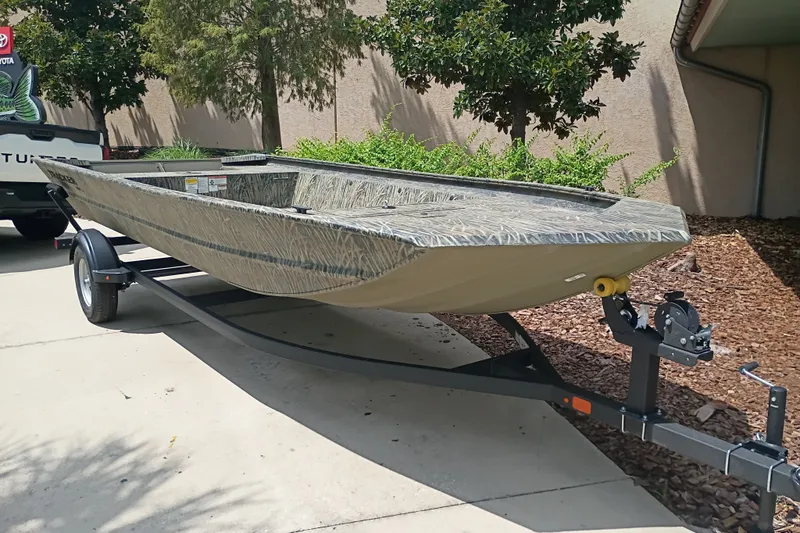 The Image of 2026 Tracker Grizzly 1860 Utility boat on trailer, parked outdoors. - 0